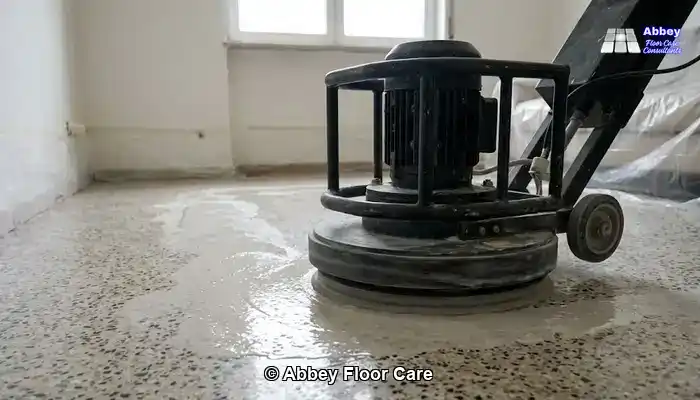 Terrazzo floor undergoing grinding with a rotary machine and visible slurry.
